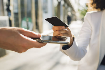 Businesswoman using credit card for payment at sidewalk cafe