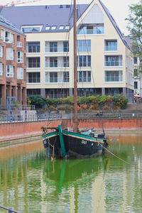 Boats moored on river by buildings in city