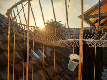 Close-up of metal fence against sky during sunset