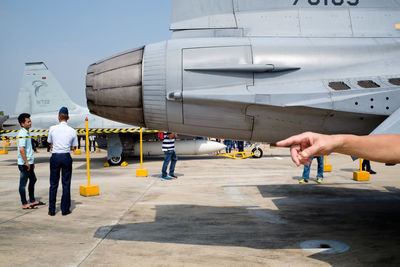 People holding airplane on runway against sky