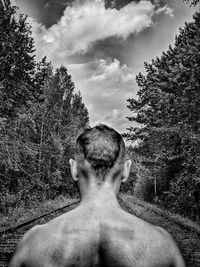 Rear view of shirtless man against sky