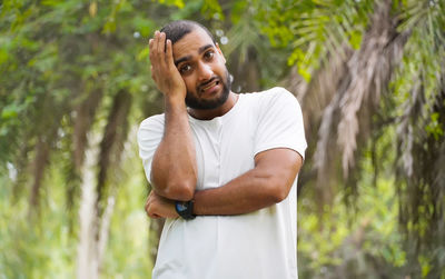 Young man looking away while standing in forest