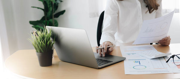 Midsection of woman using laptop on table