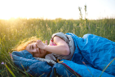 Cute girl in sleeping bag on field