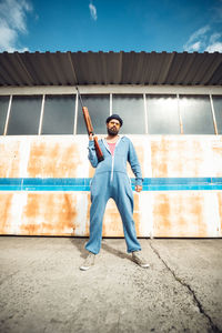 Man holding gun while standing against wall