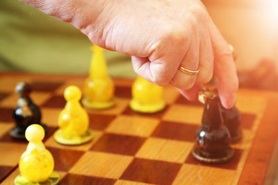 Cropped hand of person holding chess piece over board