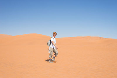 Man standing in desert against clear blue sky