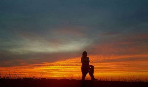 Silhouette man standing on field against sky during sunset