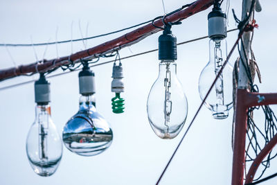 Various light bulbs hanging against sky