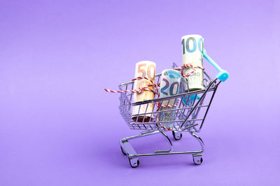 Close-up of miniature shopping cart against blue background