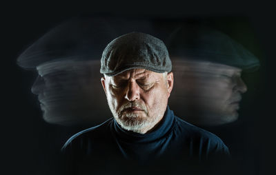 Blurred motion of senior man wearing flat cap against black background