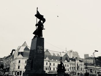 Low angle view of statue against buildings in city