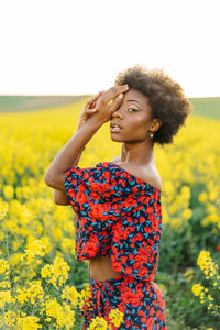 Young woman standing by yellow flower in field