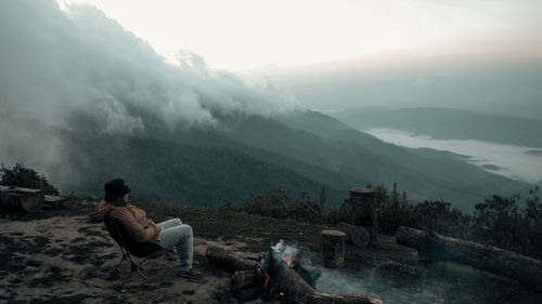 A man is sitting on the peak by the bonfire