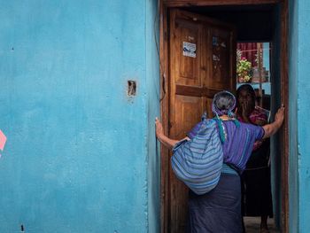 Rear view of people standing against blue door