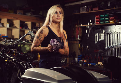 Young woman standing by motorcycle at workshop