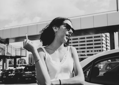 Man looking away while standing on car against sky