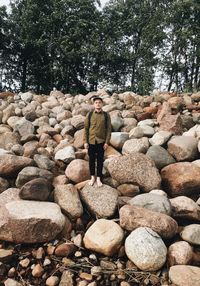 Full length of man standing on rock against trees at beach