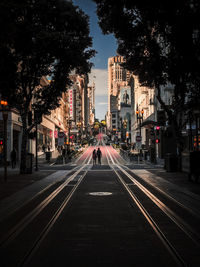 Road by illuminated buildings in city