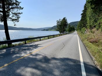 Empty road by trees against sky