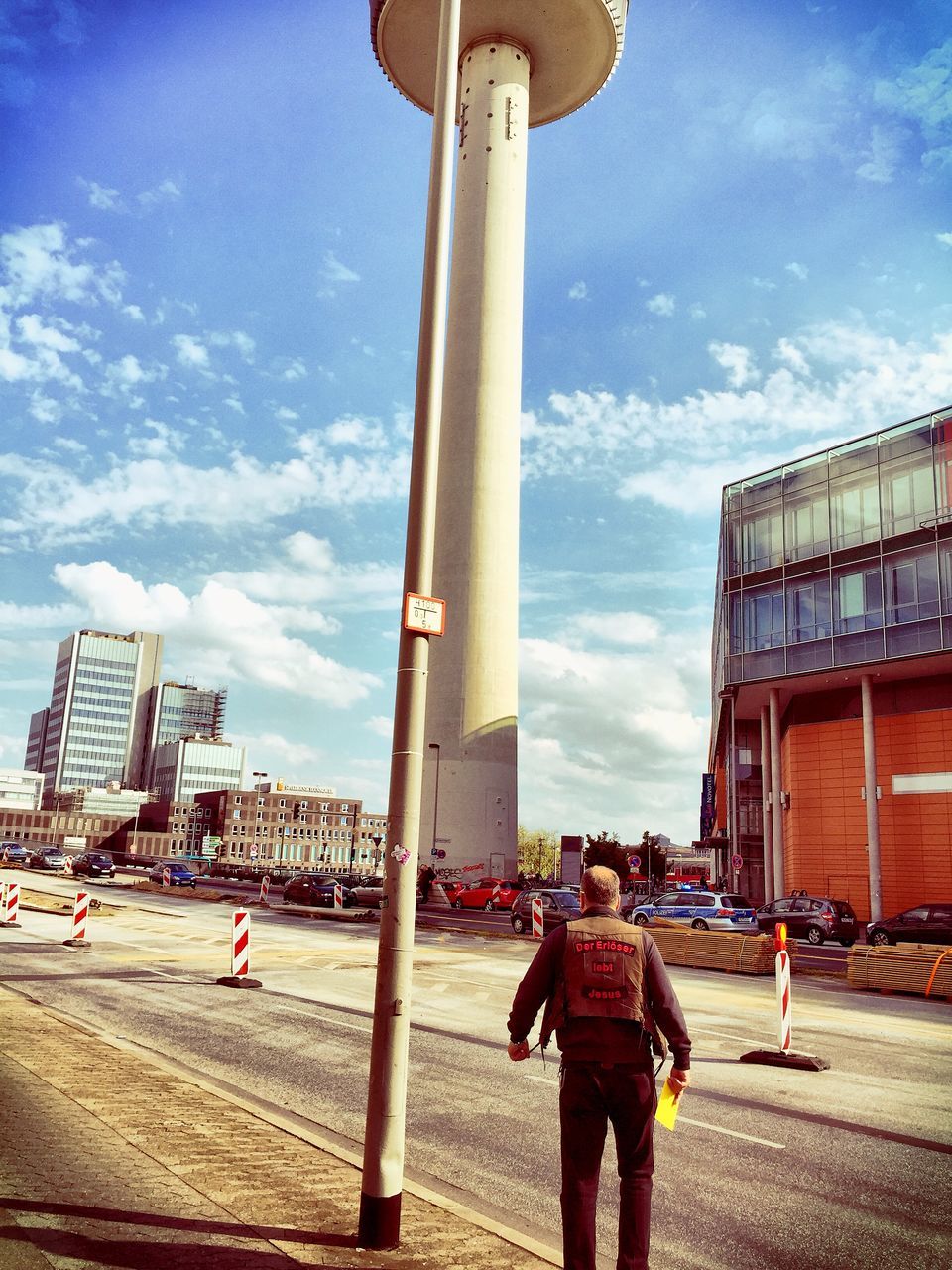 sky, architecture, built structure, lifestyles, building exterior, leisure activity, cloud - sky, person, city, walking, men, full length, casual clothing, standing, city life, cloud, rear view, sunlight