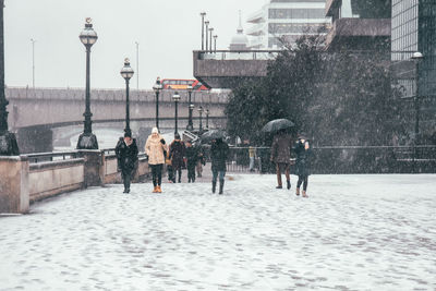 People walking on wet street in city during winter