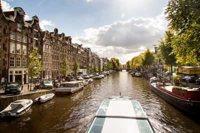 Boats moored on river in city against sky