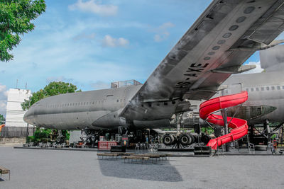 Airplane on airport runway against sky in city