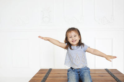 Portrait of a smiling girl standing against wall