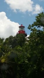 Low angle view of lighthouse amidst trees and buildings against sky