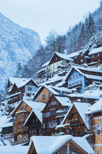 Snow covered houses by buildings against sky