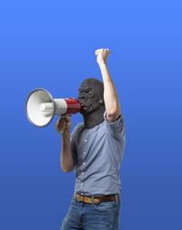 Full length of man holding camera while standing against blue sky