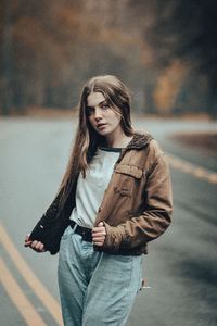 Portrait of beautiful young woman standing on road