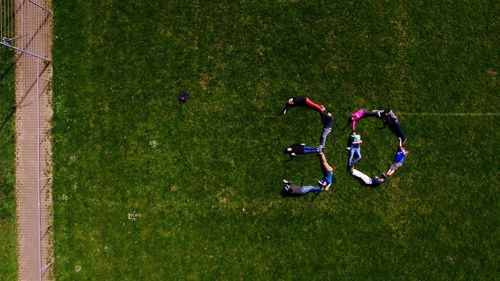 High angle view of people forming number 30 on grassy field