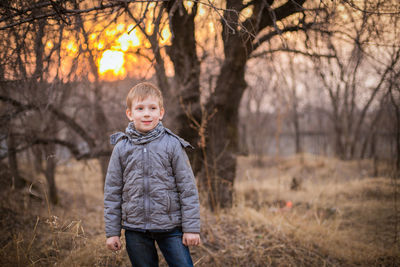 Portrait of boy standing on bare tree