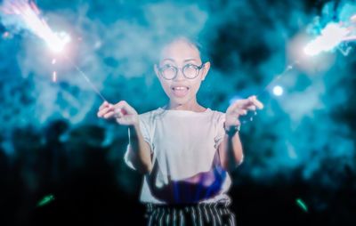 Woman holding lit sparklers at night