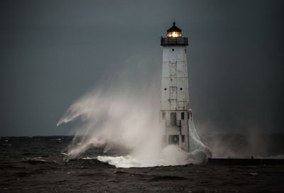 Lighthouse by sea against sky at night