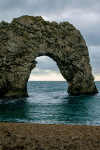 Rock formation by sea against sky