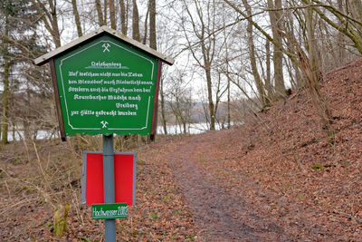 Information sign on road amidst trees in forest