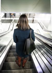 Rear view of woman on escalator