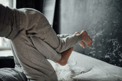 Side view of man standing on bed at home