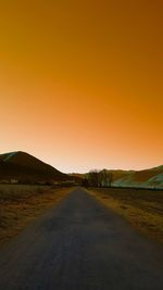 Road amidst land against sky during sunset