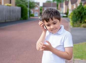 Portrait happy schoolboy talking on mobile phone with friend. cute child using smart phone 