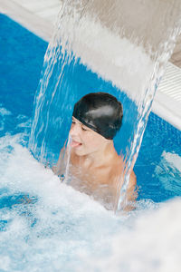 Young teenager enjoying under a waterfall jet in a spa person