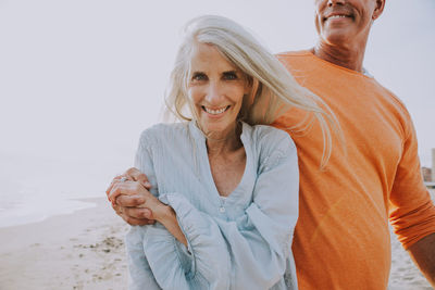 Portrait of smiling woman with boyfriend standing at beach