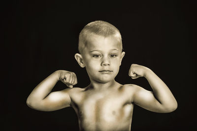 Portrait of shirtless boy against black background