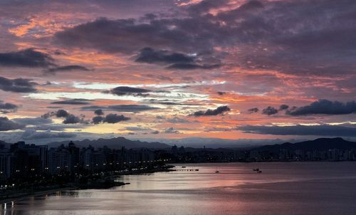 Scenic view of sea and buildings against dramatic sky