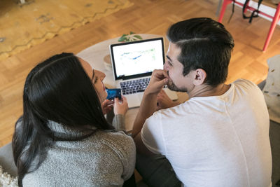 High angle view of couple shopping online through laptop on sofa at home