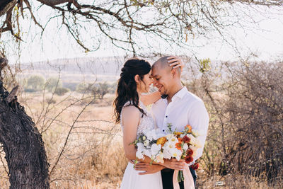 Young couple standing against plants