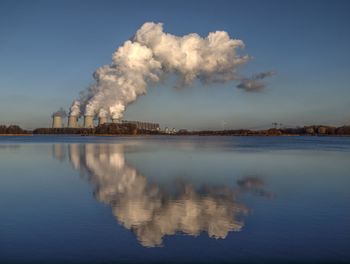 Smoke emitting from factory against sky